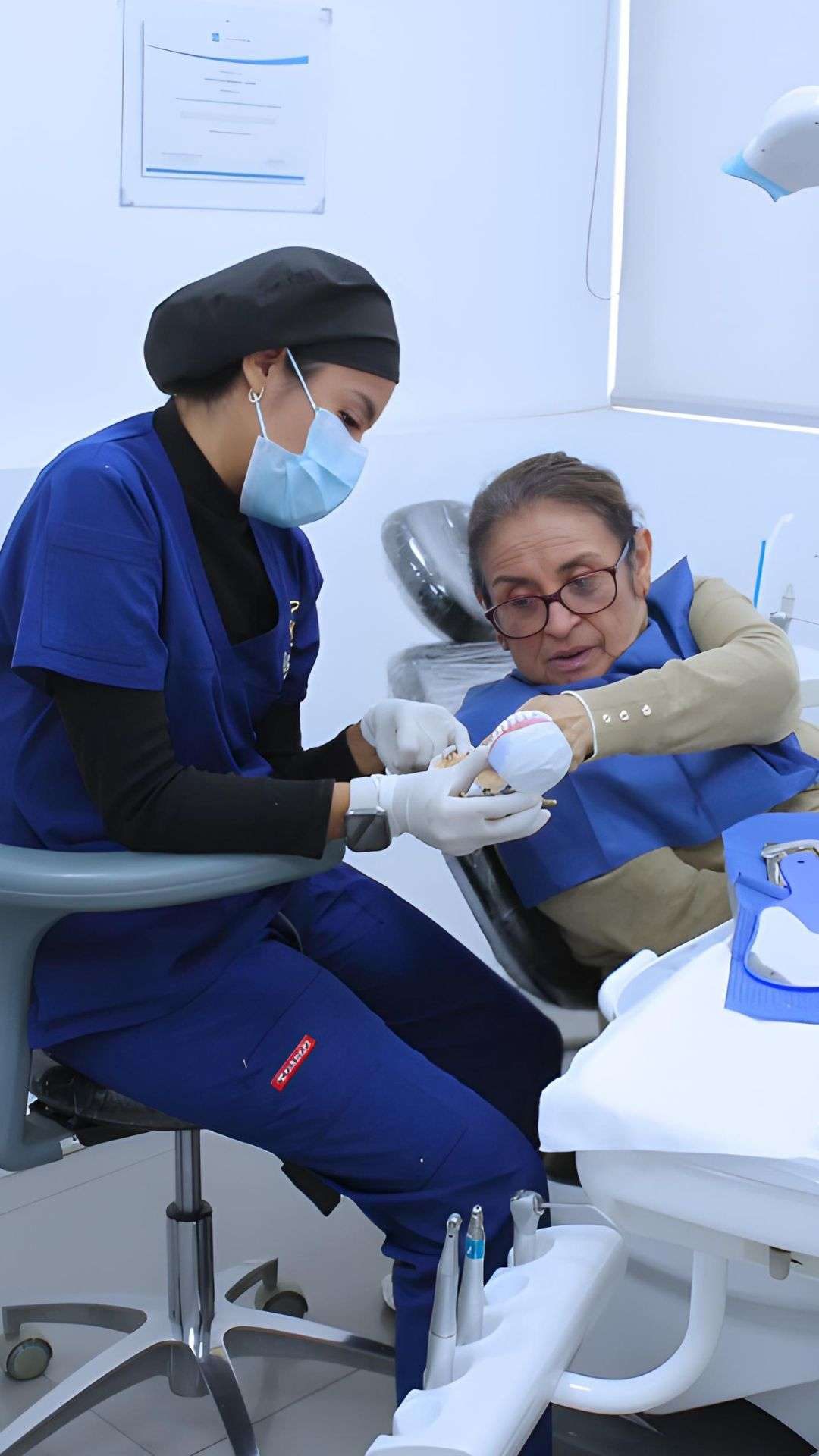 Odontóloga explicando un tratamiento con un modelo dental a una paciente